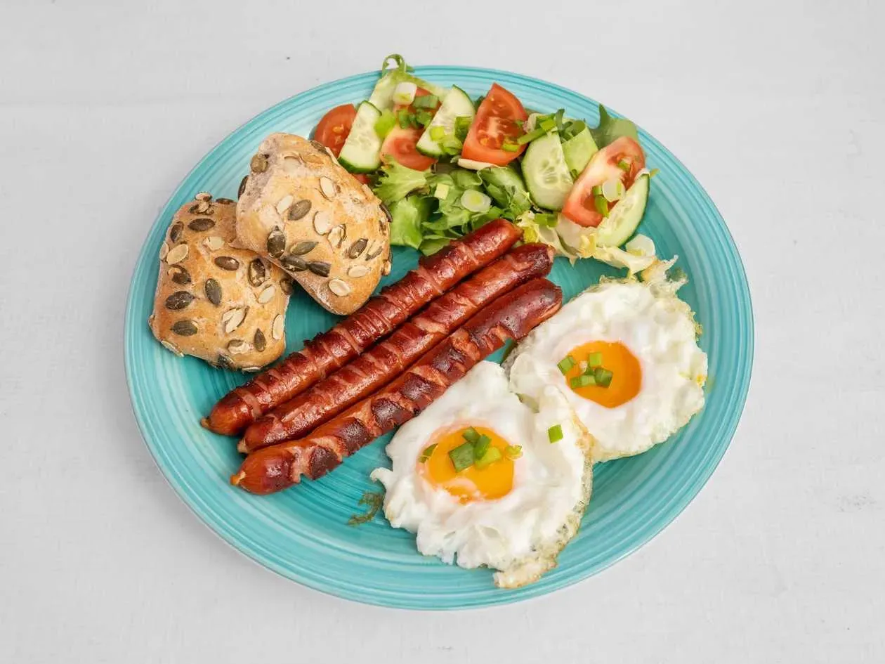 Fried Egg with Frankfurters, Bread, Butter, Cherry Tomatoes with Arugula